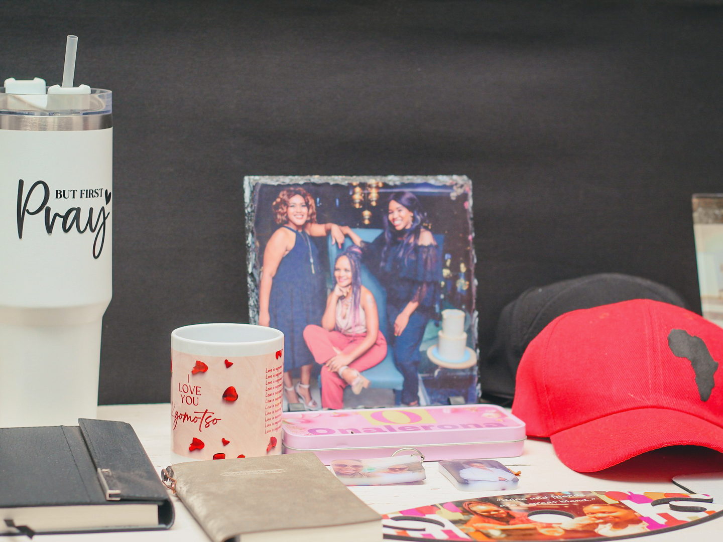 A spread of personalised products: a printed tumbler, a photo slate, a mug, a notebook and an embroidered cap.